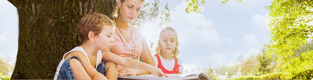 A mom reading to her two children outdoors.